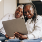 A senior couple laugh and use a tablet together.  